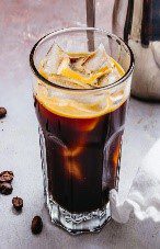 A glass of coffee with ice in it.