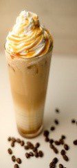 A tall glass of coffee with whipped cream on top.